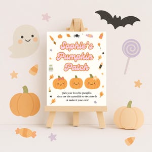 Può includere: Un cavalletto di legno espone un cartello per "Sophie's Pumpkin Patch" con zucche arancioni ed elementi decorativi. Il cartello incoraggia i visitatori a scegliere e decorare le proprie zucche. Ulteriori decorazioni a tema Halloween.