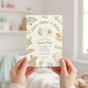 Puede incluir: Invitación a un baby shower con el texto "Bams, Bottles, & Babies" y el nombre "Louise Trent". La invitación presenta ilustraciones en acuarela de artículos para bebés como un osito de peluche, un pato y dados.