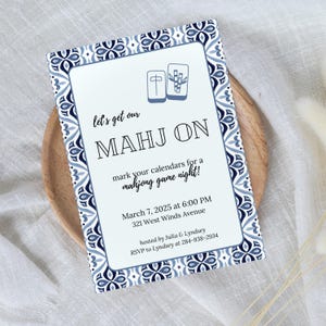 May include: A blue and white patterned invitation card with a Mahjong tile design. The text reads "Let's get our Mahj On" and includes details for a Mahjong game night on March 7, 2025 at 6:00 PM at 321 West Winds Avenue. The invitation is hosted by Julia & Lyndsey and requests RSVP to Lyndsey at 284-938-2934.