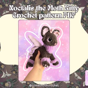 Puede incluir: Un peluche de ganchillo marrón oscuro y morado claro que se asemeja a un híbrido de gato y polilla con grandes ojos oscuros, detalles de pelaje morado claro y alas pálidas. El texto Noctalis the Moth Kitty Crochet pattern PDF aparece arriba.