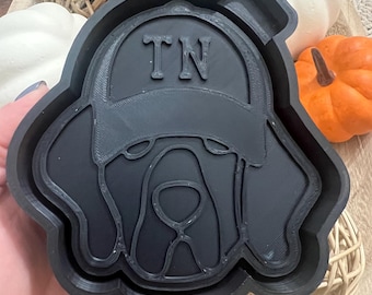 May include: Black silicone mold of a dog wearing a baseball cap with the letters "TN" on it.