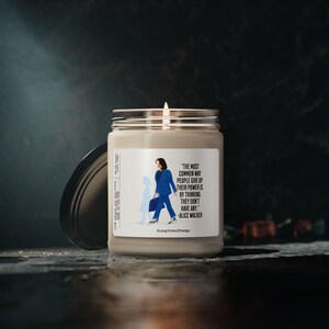 Op de afbeelding: Een glazen potkaars met een zilveren deksel, met een label met een illustratie van een persoon in een blauw pak en de quote "De meest voorkomende manier waarop mensen hun macht opgeven, is door te denken dat ze er geen hebben." -Alice Walker.