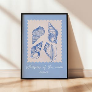 May include: A framed art print featuring four blue seashell illustrations on a light blue background. The print includes the text "Whispers of the ocean" and "GREECE". The artwork is displayed in a black frame.