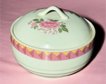 Azucarero de cerámica con diseño floral y tapa, redondo, brillante, en tonos rosa, verde y amarillo.