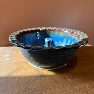 Bol de cerámica Studio Pottery con forma de manzana, esmalte reactivo azul-marrón y borde festoneado.