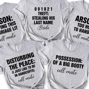 May include: Five light gray t-shirts with black text. The shirts have phrases like "ARSON: KEEPING THIS MARRIAGE LIT" and "POSSESSION: OF A BIG BOOTY." Each shirt says "cell mate" at the bottom.