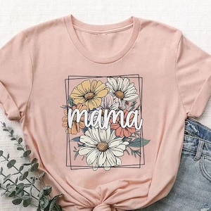 May include: A pink t-shirt with a floral design and the word "mama" in white text. The flowers are yellow, pink, and white.