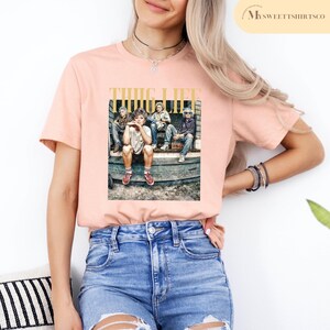 May include: A pink t-shirt with a graphic print of four people sitting on a stoop. The graphic includes the text "THUG LIFE".