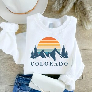 a white shirt that says colorado with mountains and trees on it