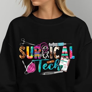 May include: Black sweatshirt with a colorful graphic design that says "SURGICAL Tech" with medical tools and a face mask.