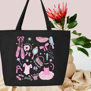 May include: Black tote bag with a pink and white design featuring a ballerina, ballet shoes, leg warmers, a hair scrunchie, and a crown. The text "My Princess" is printed on the bag.