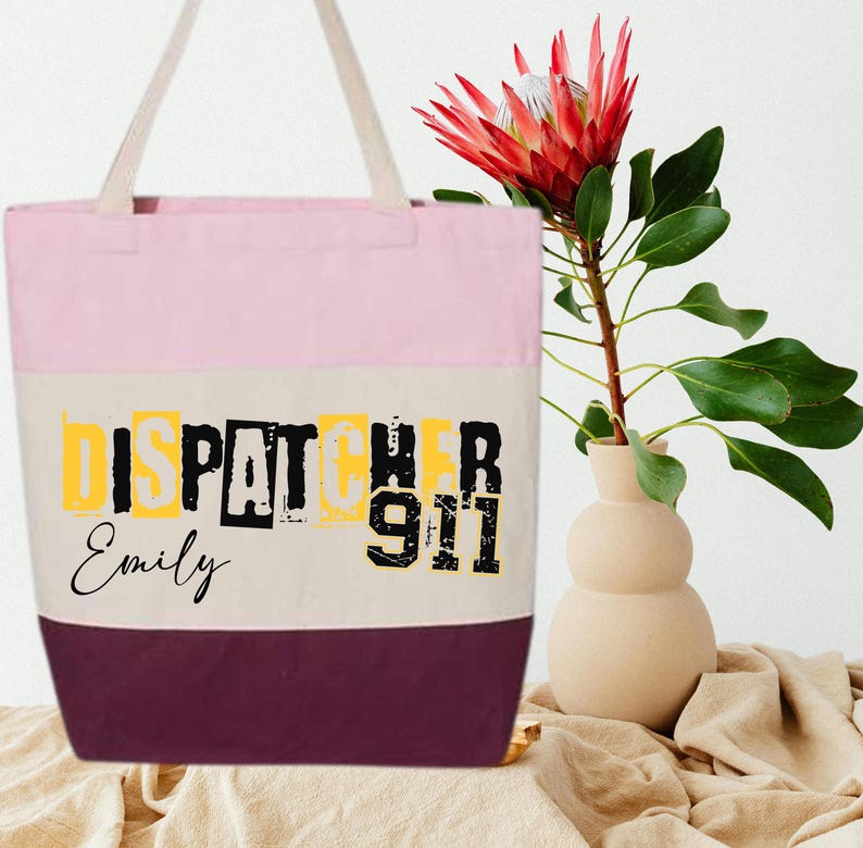 May include: Pink, beige, and burgundy tote bag with the text "Dispatcher 911" in black and yellow letters. The name "Emily" is written in cursive below the text.