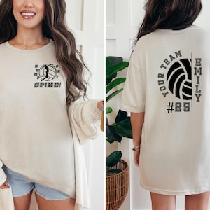 May include: An oversized beige t-shirt with a volleyball graphic and the text "SPIKE!" on the front and "YOUR TEAM EMILY #28" on the back.