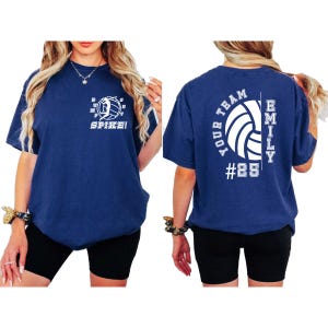 May include: A navy blue t-shirt with a white volleyball graphic and the text "Spike!" on the front. The back of the shirt has the text "Your Team" and "Emily #25" with a volleyball graphic.