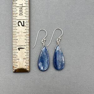 K&ouml;nnte beinhalten: Ein Paar silberne Tropfenohrringe mit blauen Kyanit-Steinen. Die Ohrringe sind etwa 2,5 cm lang.