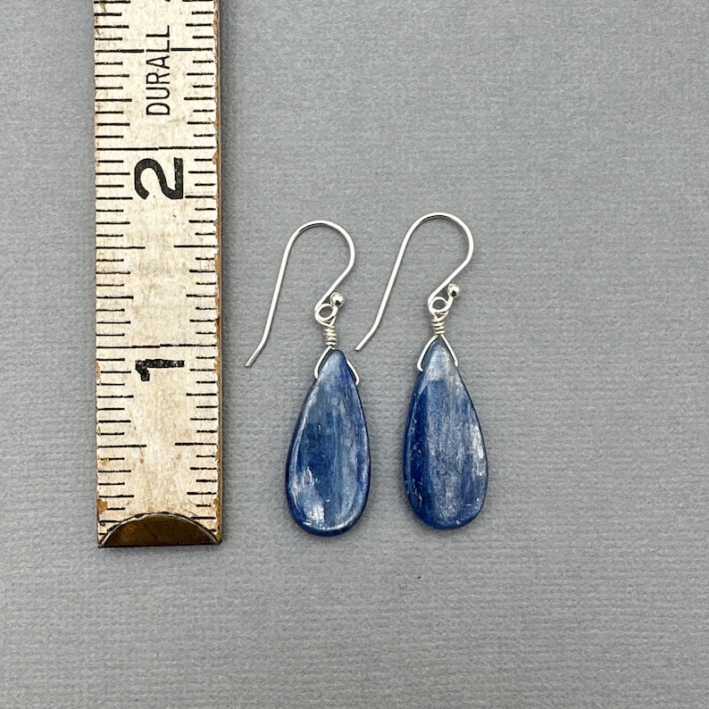 K&ouml;nnte beinhalten: Ein Paar silberne Tropfenohrringe mit blauen Kyanit-Steinen. Die Ohrringe sind etwa 2,5 cm lang.