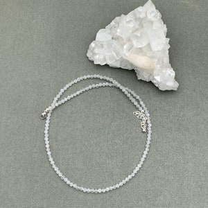 Puede incluir: Un delicado collar de piedra lunar blanca con cierre de plata. El collar est&aacute; hecho de peque&ntilde;as cuentas redondas y mide aproximadamente 45 cm de largo.