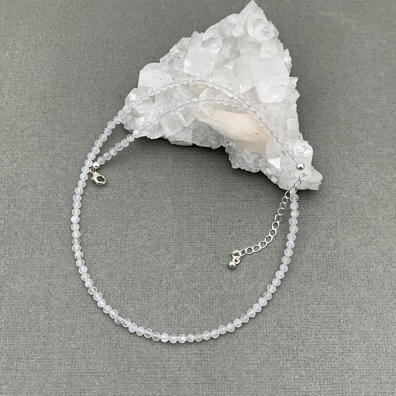 Puede incluir: Un delicado collar gargantilla de piedras preciosas blancas con un extensor de cadena plateado. El collar est&aacute; hecho de peque&ntilde;as cuentas redondas y es perfecto para superponer.