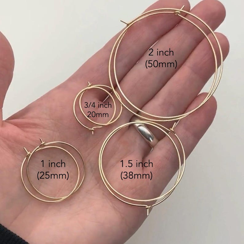 Op de afbeelding: Een verzameling goudkleurige oorringen in verschillende maten: 20 mm, 25 mm, 38 mm en 50 mm. De oorbellen worden getoond tegen een neutrale achtergrond.