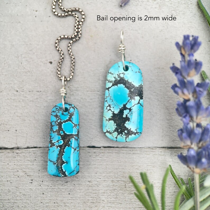 May include: Two turquoise pendants with silver chains and wire wrapping. The pendants are rectangular with rounded edges and feature a vibrant blue colour with black matrix patterns. The bail opening is 2mm wide. One pendant is attached to a chain, the other is separate.