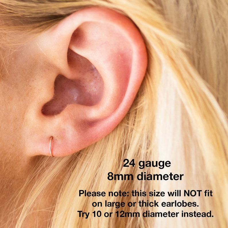 May include: Close-up of a person's ear with a small 8mm diameter, 24 gauge hoop earring. The text reads: "24 gauge 8mm diameter Please note: this size will NOT fit on large or thick earlobes. Try 10 or 12mm diameter instead."