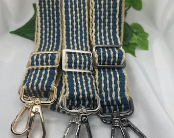 May include: Three woven bag straps with blue and beige vertical stripes. Each strap has a different metal clasp: gold, silver, and gunmetal. The straps are displayed against a white background.