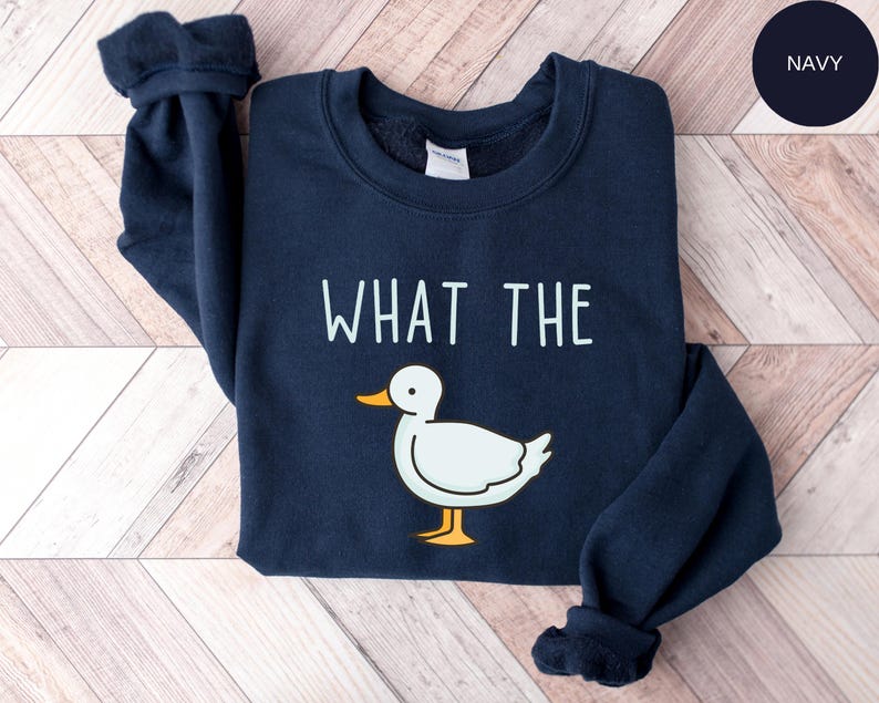 May include: A navy blue sweatshirt with the text "WHAT THE" printed in white and a cartoon duck illustration.