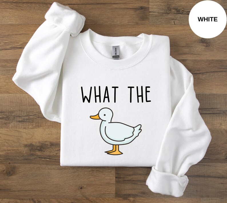 May include: White crewneck sweatshirt with the text "WHAT THE" and a cartoon duck illustration.
