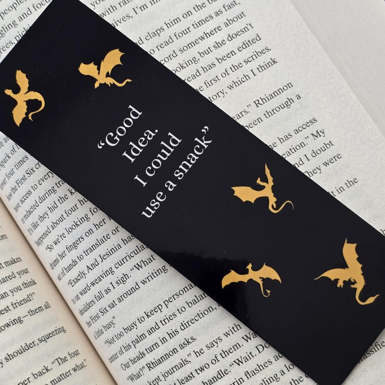May include: Black bookmark with gold dragon silhouettes and the text "Good Idea. I could use a snack."