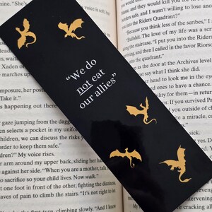May include: Black bookmark featuring gold dragons and the text "We do not eat our allies".