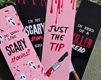 May include: Four pink and black bookmarks with horror movie themes. One bookmark says "Do you like scary stories?" with a ghost face mask pattern. Another says "In my scary story era" with a dripping blood design. A third bookmark says "Just the tip" with a bloody knife. The last bookmark says "In need of a killer read" with a ghost face mask and a knife.