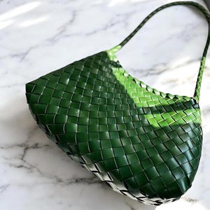 May include: A dark green woven leather handbag with a single strap.
