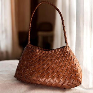 May include: A brown woven leather handbag with a single top handle.
