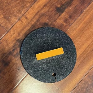 May include: A black round lid with a small hole in the center and a yellow rectangular handle.
