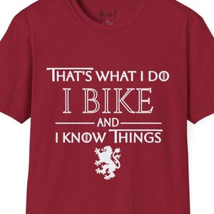 Könnte beinhalten: Rotes T-Shirt mit weißem Text, der "That's what I do I bike and I know things" lautet. Unter dem Text befindet sich eine weiße Löwengrafik.