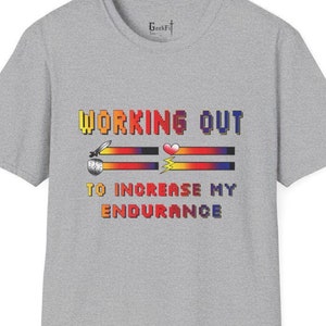 May include: Gray t-shirt with a pixelated graphic that says "WORKING OUT TO INCREASE MY ENDURANCE". The graphic is in shades of red, orange, yellow, and blue.