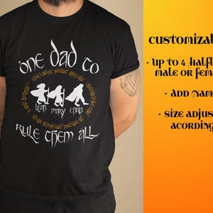Może przedstawiać: Czarna koszulka z białym tekstem i okrągłą grafiką z trzema postaciami. Tekst brzmi "one dad to rule them all" z dodatkowym tekstem wokół grafiki. Koszulka ma również słowa "customizable" i inny tekst.