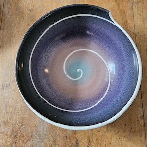 May include: A ceramic bowl with a white rim and a swirling purple, blue, and pink design.