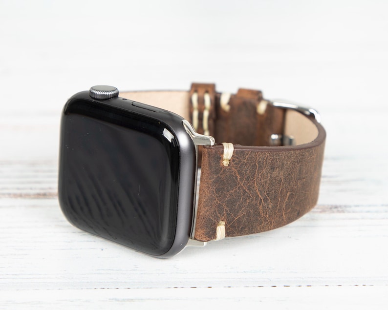 May include: A black smartwatch with a brown leather band. The band has a distressed, textured appearance with visible stitching. The watch is set against a white background.