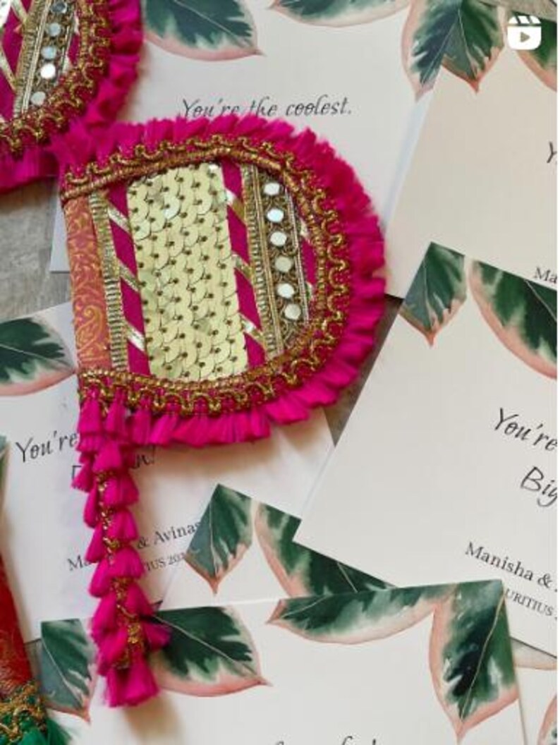 May include: A vibrant pink and gold decorative fan with a tassel fringe. The fan features gold sequins, mirrors, and decorative trim. The text "You're the coolest" is visible on the surrounding cards. The fan is likely used for a special occasion.