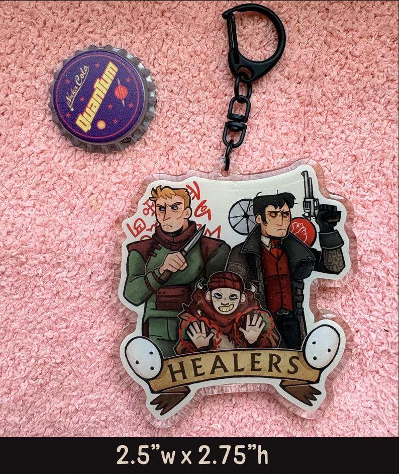 May include: An acrylic keychain featuring three illustrated characters and the text HEALERS, measuring 2.5 inches wide by 2.75 inches high, accompanied by a circular Nuka Cola Quantum bottle cap with a purple background and yellow text.