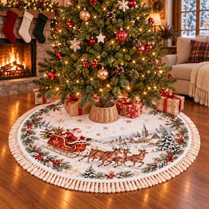 May include: A round white Christmas tree skirt featuring a printed scene of Santa Claus in a red sleigh pulled by reindeer, surrounded by a winter village landscape, pine branches, and red berries, finished with a cream-coloured fringe border.
