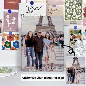 May include: A personalized iPad case featuring a family photo in front of the Eiffel Tower. The case has a white border and the family's last name, "Barnett," is printed on the bottom. The background includes decorative cards and a small angel statue.