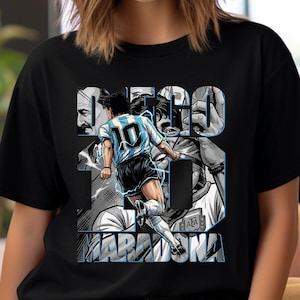 May include: Black t-shirt featuring a graphic of a soccer player in a blue and white uniform, with the number 10 on the back. The design includes the text "DIEGO MARADONA" in a stylized font, with a background of grayscale images.