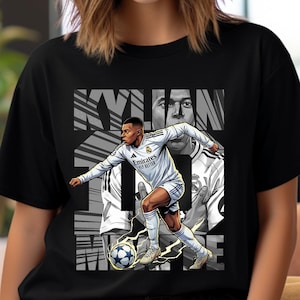 以下が含まれることがあります： 黒いTシャツ。白いユニフォームを着たサッカー選手のグラフィックと「KYLIAN MBAPPE」の文字。デザインには、選手のグレースケール画像とサッカーボールが含まれています。Tシャツは半袖です。