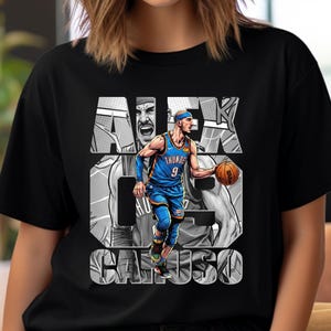 Op de afbeelding: Zwart t-shirt met een afbeelding van basketballer Alex Caruso in een blauw en oranje tenue, met een basketbal. De naam en het rugnummer van de speler staan in grote witte letters.