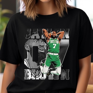 Puede incluir: Camiseta negra con un gráfico de un jugador de baloncesto con una camiseta verde y blanca. El diseño incluye la palabra "BOSTON" y el número "7". También presenta un retrato en escala de grises del jugador y el nombre "JAYSON TATUM".