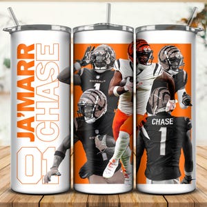 May include: A white tumbler with a silver lid and straw, featuring a design of football players in black and orange uniforms. The name "JA'MARR CHASE" and the number "01" are printed in orange.