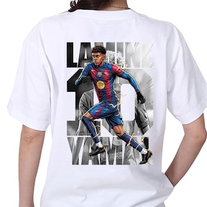 May include: White t-shirt featuring a graphic of a soccer player in a blue and red uniform, with the name "LAMINE" and the number "19" printed on the back. The design includes a Spotify logo and the text "UNHCR AC NUR".