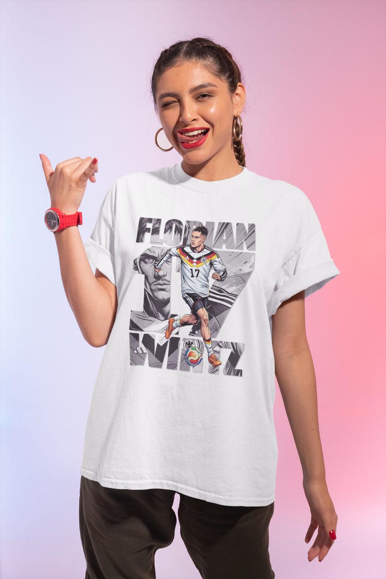 May include: White t-shirt featuring a graphic of a soccer player in a German national team uniform, with the name "FLORIAN" and the number "17" printed on it. The design includes a portrait and the name "WIRTZ".